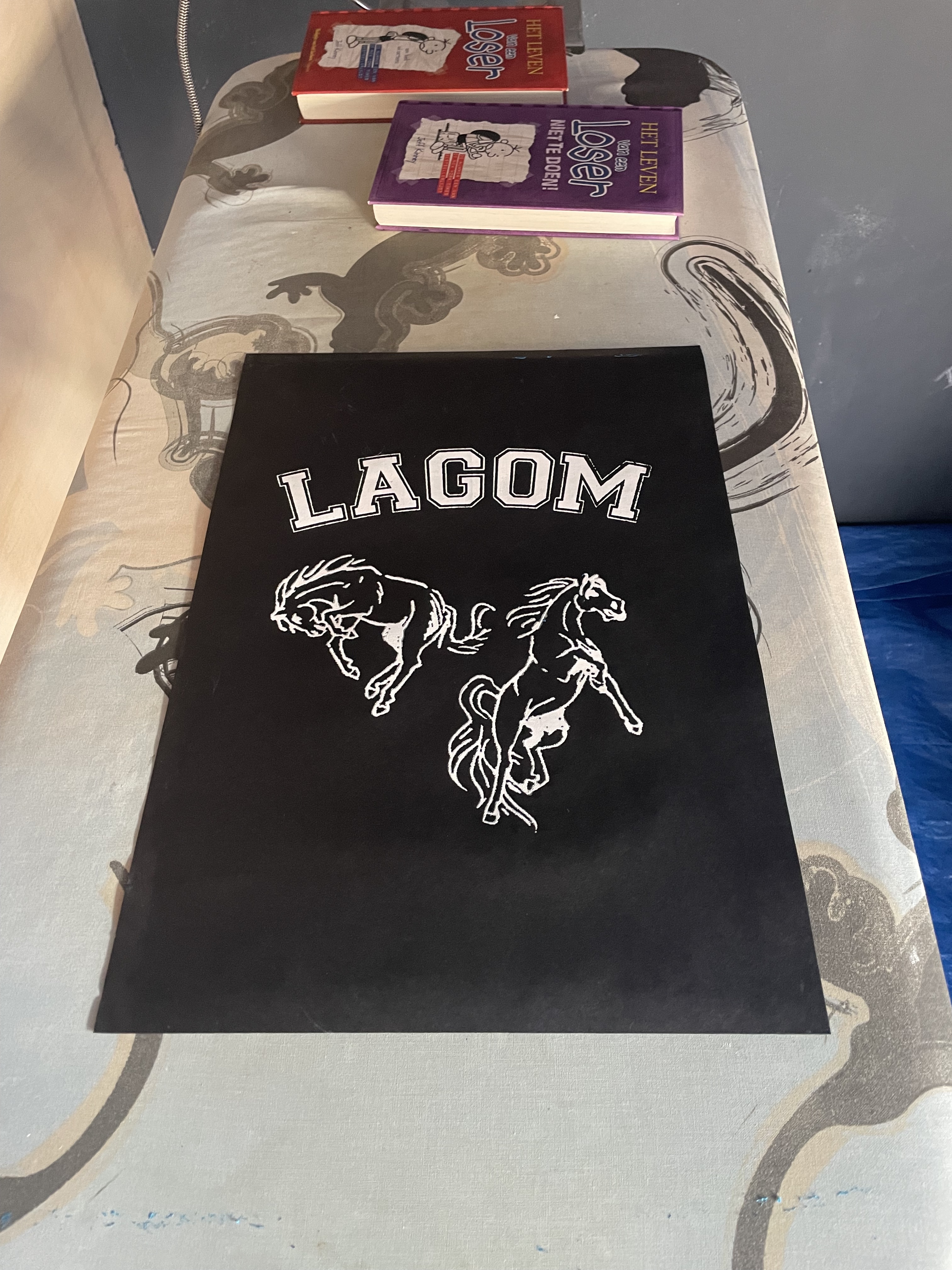 foto van een zwart A3 fel. met daarop 2 paarden bedrukt en de text Lagom.